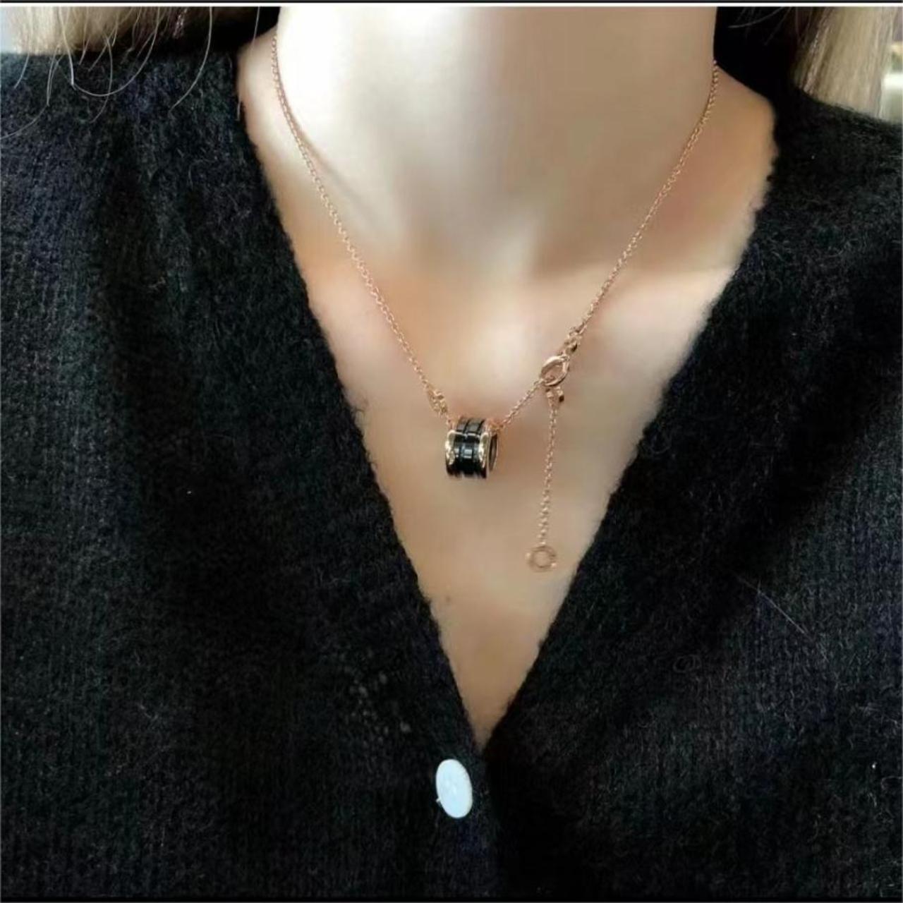 Rose gold necklace with a pendant on a black sweater