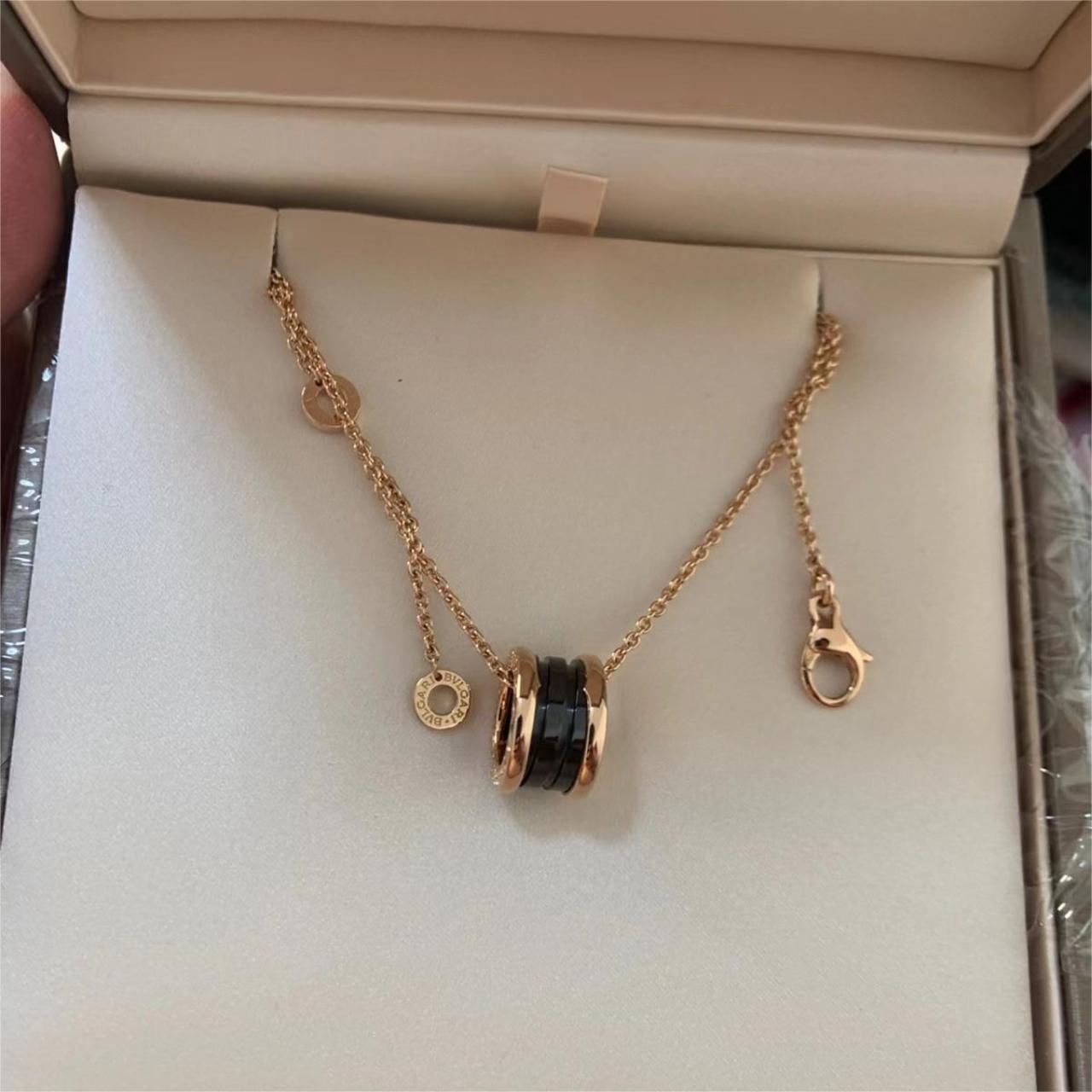 Gold necklace with a black and gold pendant in an open jewelry box.
