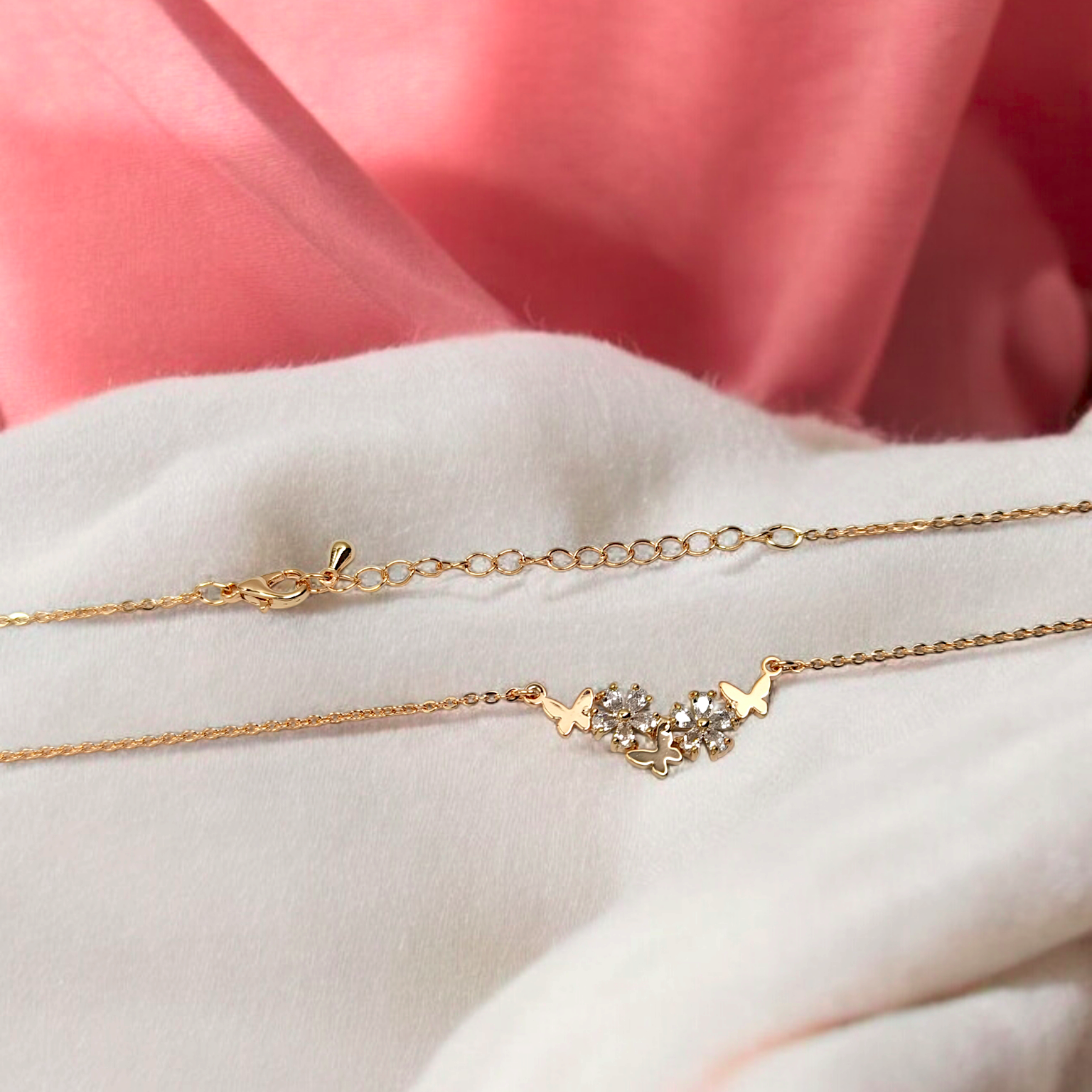 Gold necklace with star and heart design on a white surface