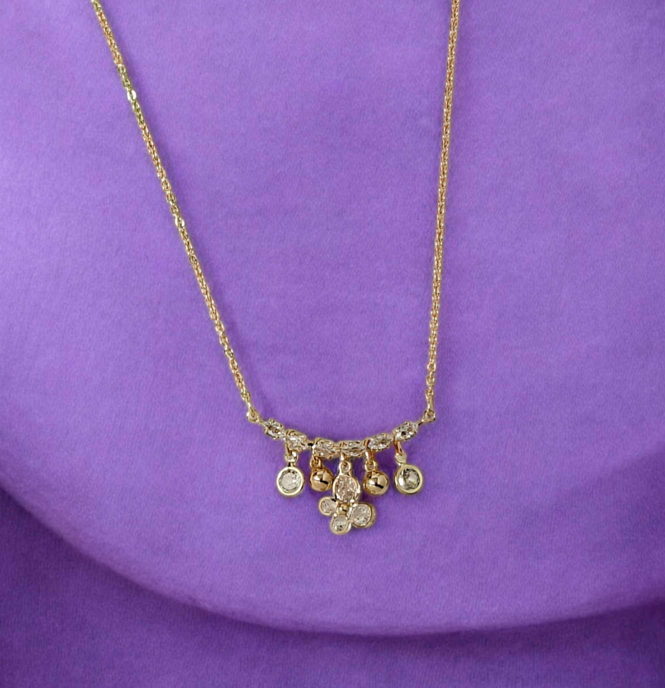 Gold necklace with floral pendant on a purple background