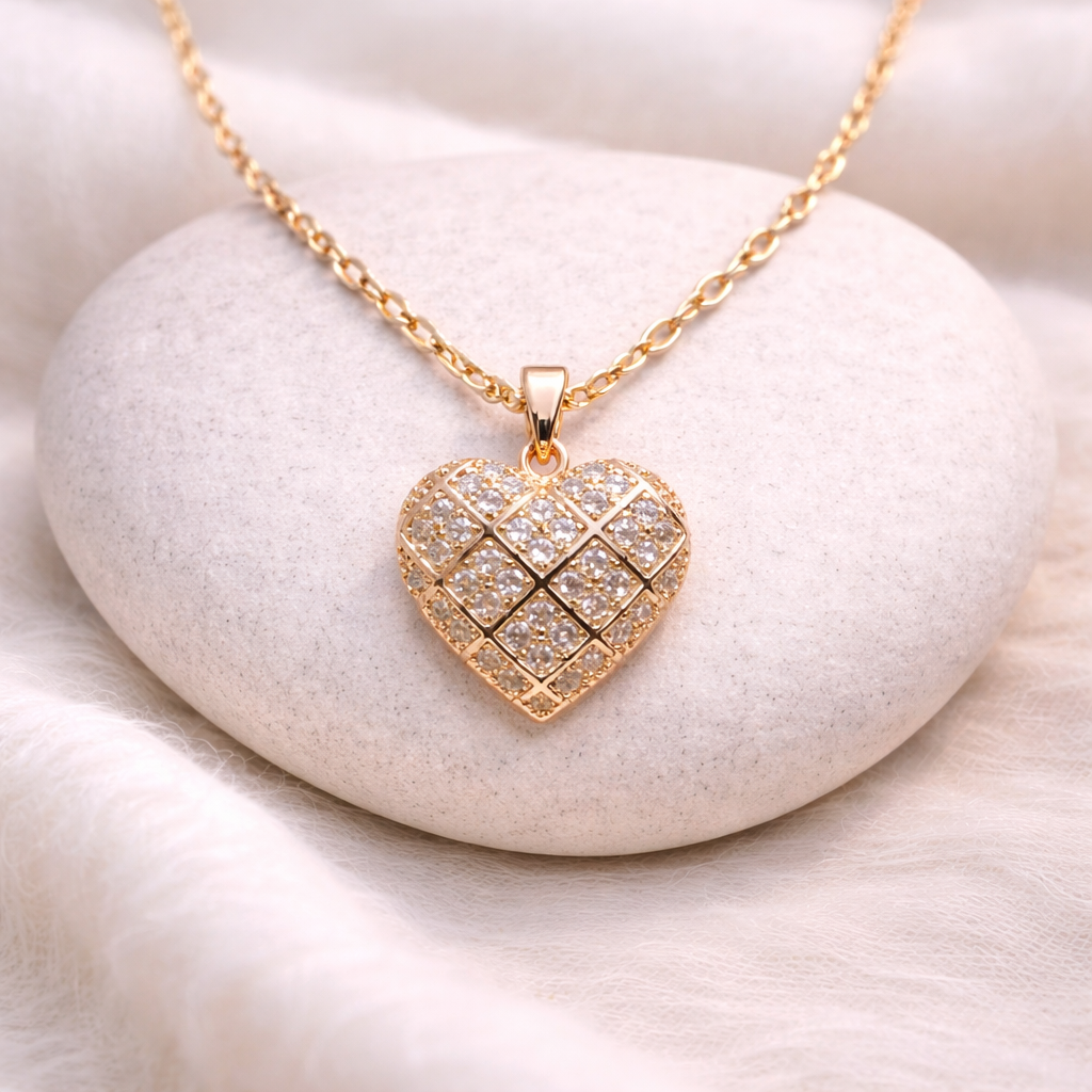 Gold heart-shaped necklace with diamond-like stones on a white stone surface