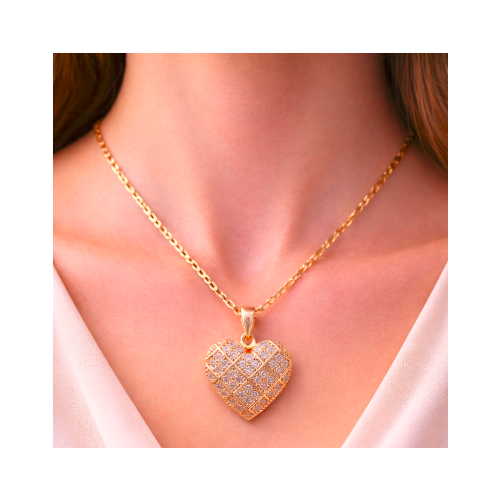 Gold heart-shaped necklace with a diamond pendant on a person wearing a white top.