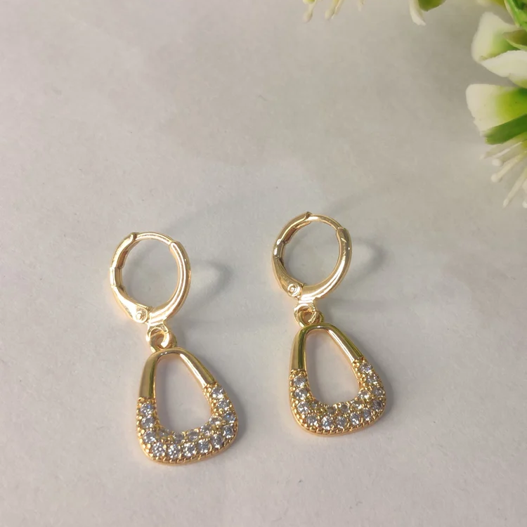 Gold earrings with clear stones on a light background