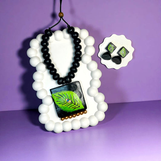 Handcrafted Leaf Pendant Set featuring black bead necklace and matching leaf design earrings on white display 