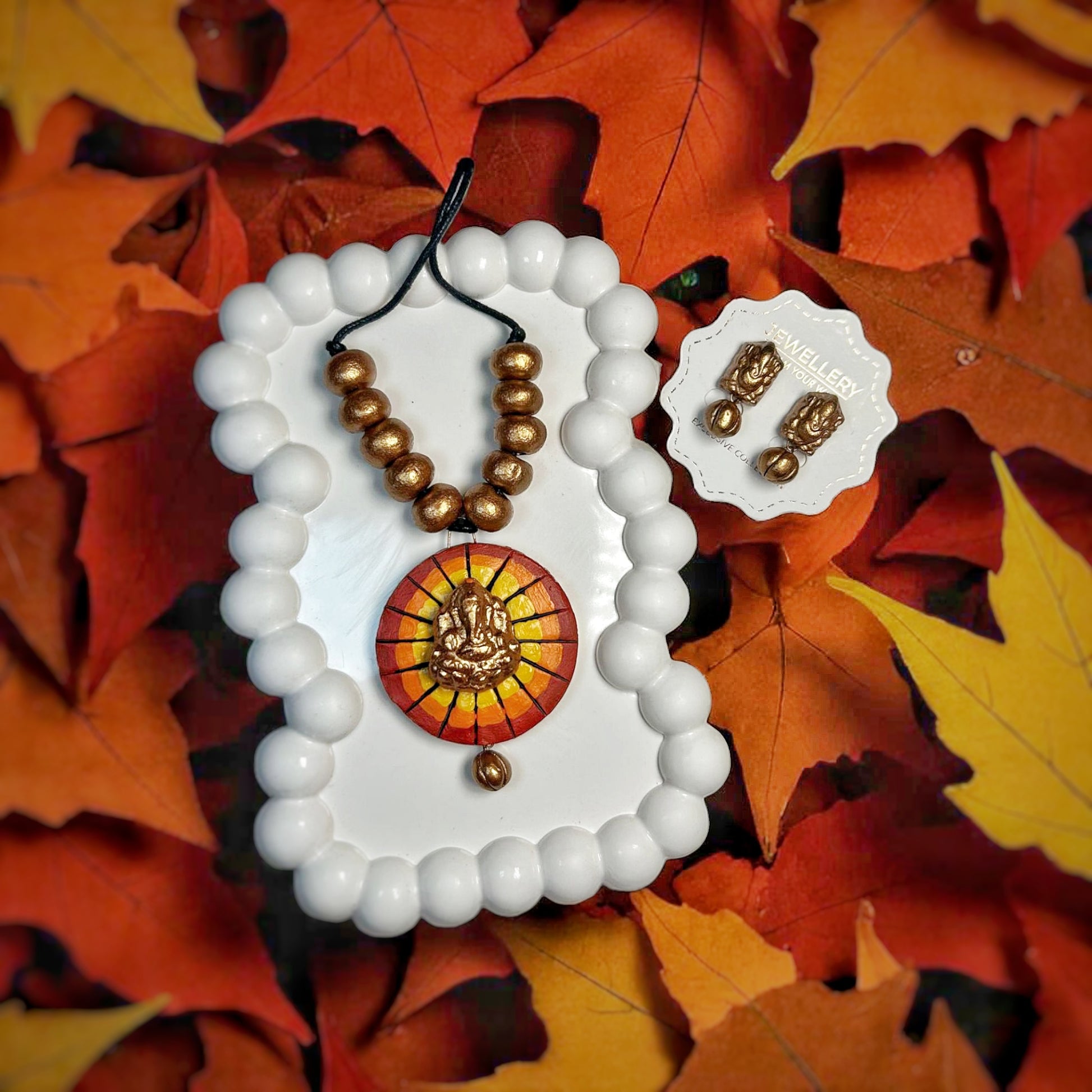 Handmade Jewelry Ganesha Necklace And Earring set with brown beads on autumn leaves background