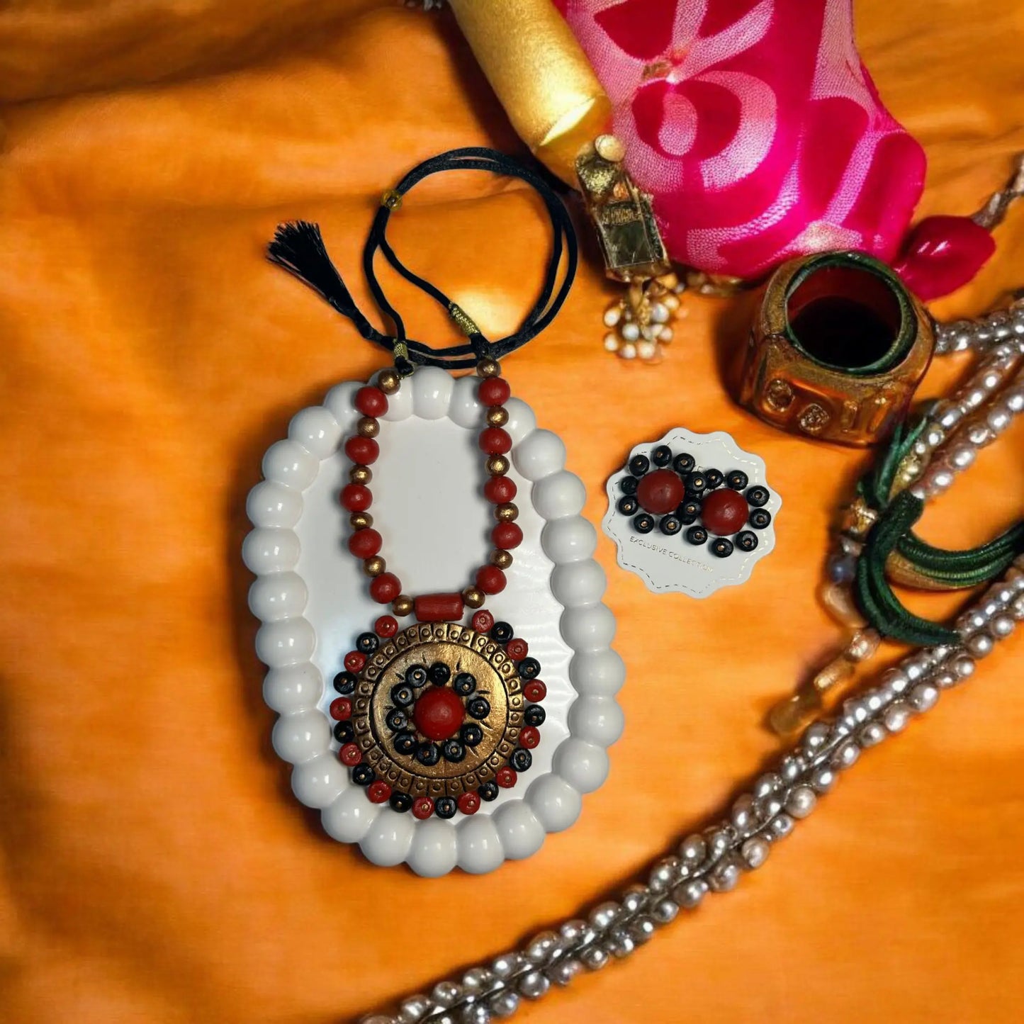 Handmade red mandala jewelry necklace and earrings set displayed on white beads and orange background by ASTRIA JEWELLERY